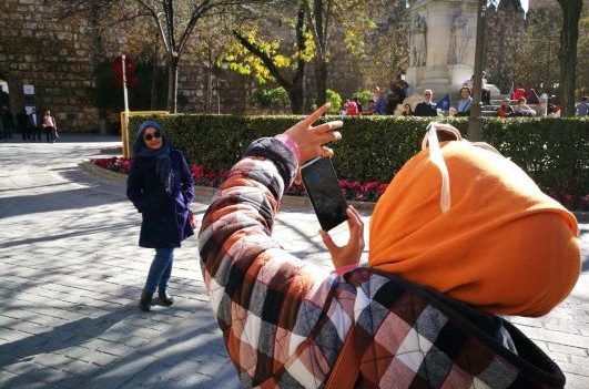 Two Indonesian tourists taking photos by the Royal Alcázar of Seville, Spain
