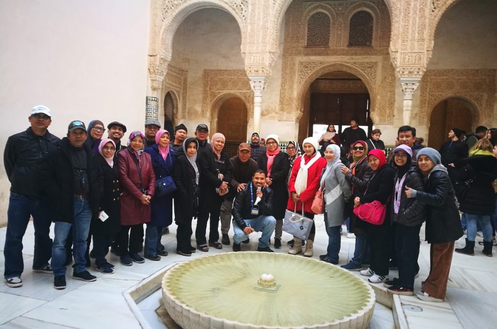A large group of Muslim tourists posing with their guide during their visit to the Alhambra in Granada.